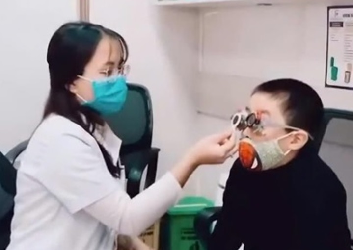A photo of Vietnam optometry graduate, An Dung, examining a young child's eyes